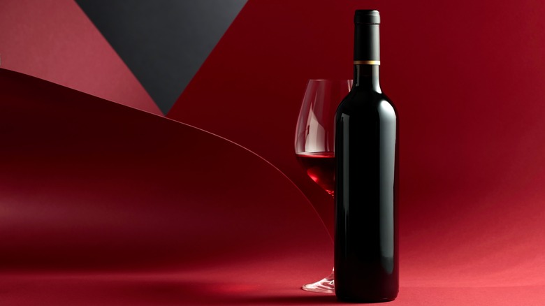 a bottle of red wine next to a glass
