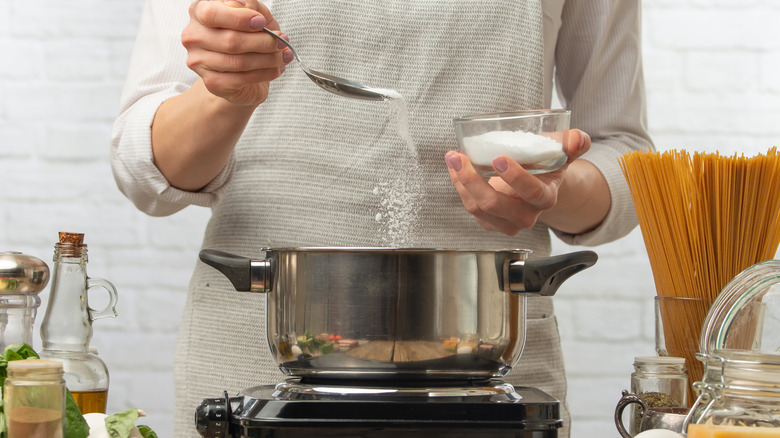 chef adding salt to pot of water