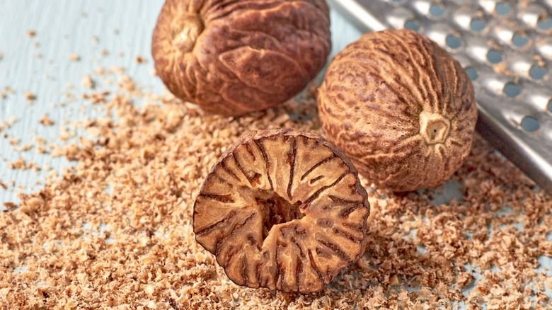 Close up of whole and freshly grated nutmeg with microplane