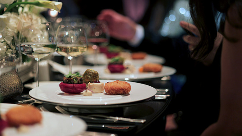 Plates of food in front of guests at fine dining restaurant.