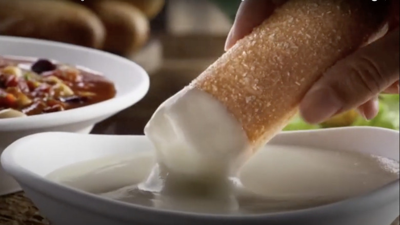 A breadstick being dipped in sauce in an Olive Garden commercial.