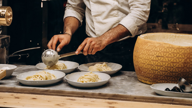 Chef preparing four plats of pasta in a professional kitchen