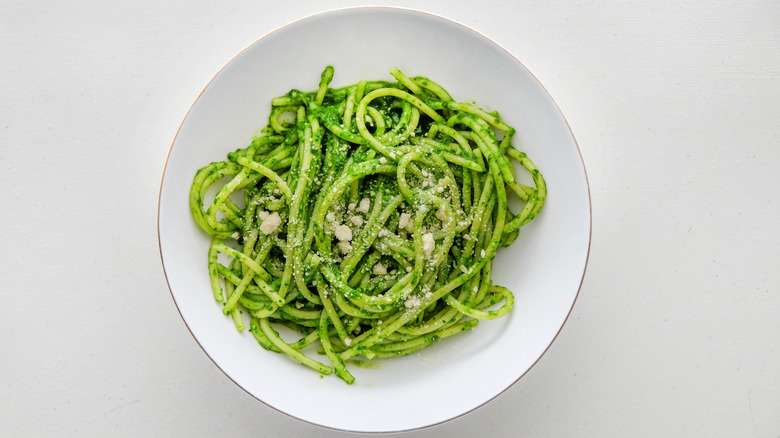 Green spaghetti noodles on a white plate isolated