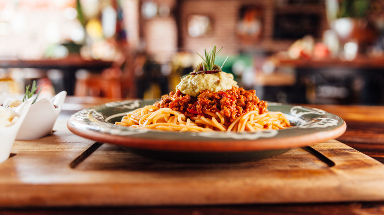 Plate of spaghetti Bolognese on a plate sitting on a cutting baord
