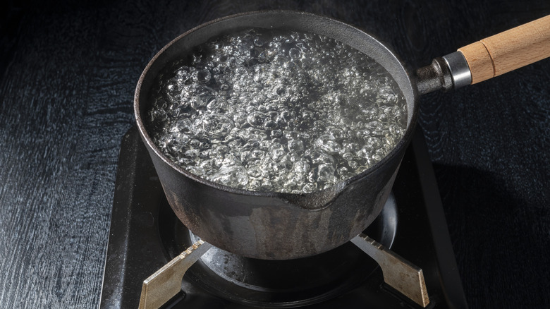 Water boiling in an iron pot on a gas stovetop