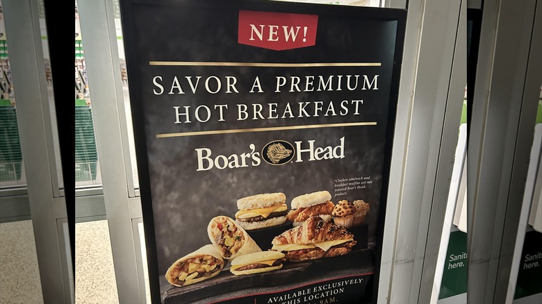 A Publix sign that says "New! Savor a premium hot breakfast" with the Boar's Head logo and several sandwiches