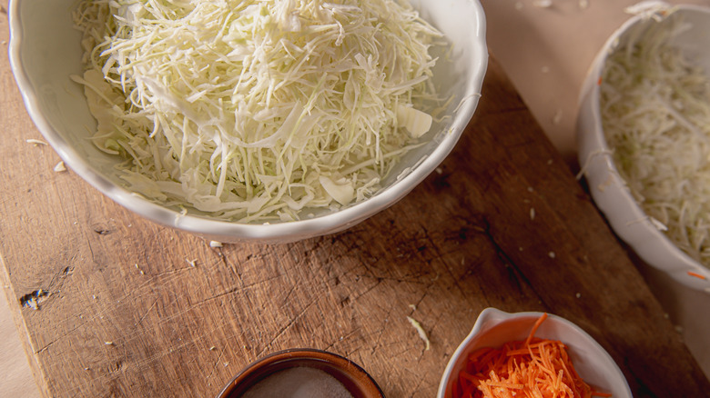 Grated cabbage and carrots in bowls and salt
