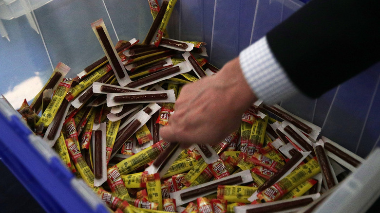 man's hand reaching into pile of slim jims
