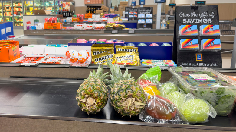 Plastic-wrapped produce on the belt in an Aldi checkout aisle