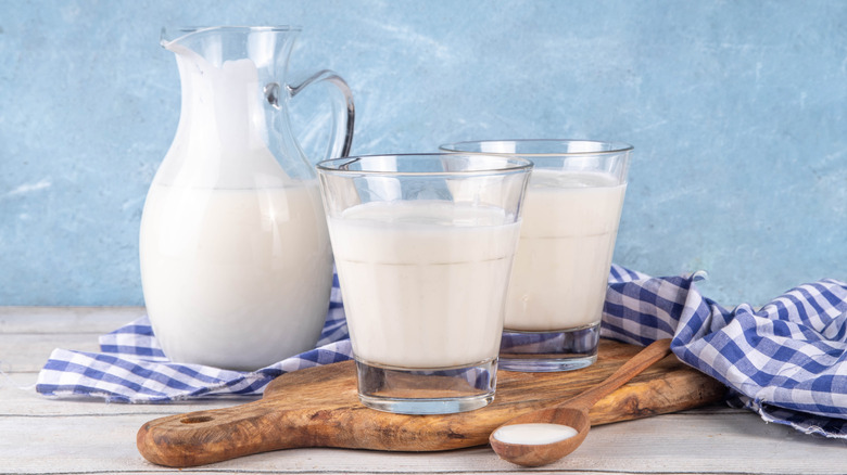Pitcher and glasses of buttermilk on cutting board