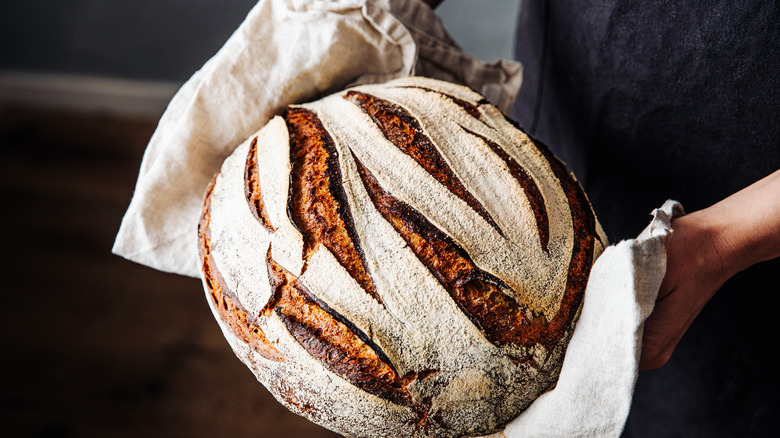 person holding loaf of sourdough bread