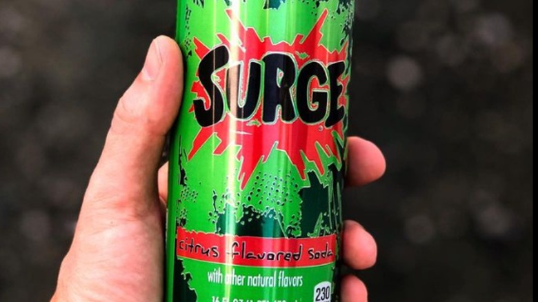 person holding can of surge