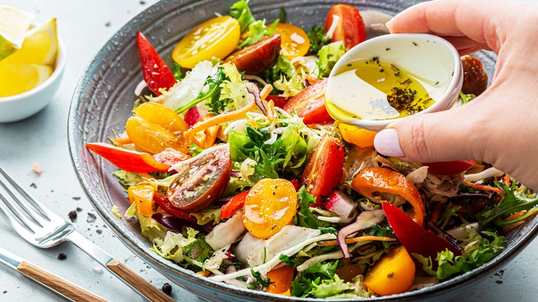pouring oil dressing on salad