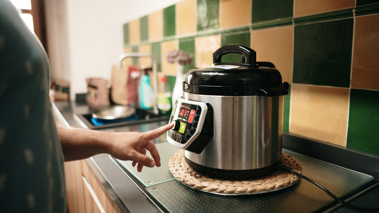 person adjusting settings on a slow cooker