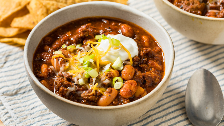 chili in a bowl with sour cream, shredded cheese, and green onions