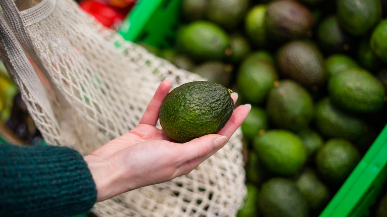 A woman holds an avocado 