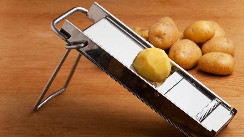 Potatoes and silver mandoline on table