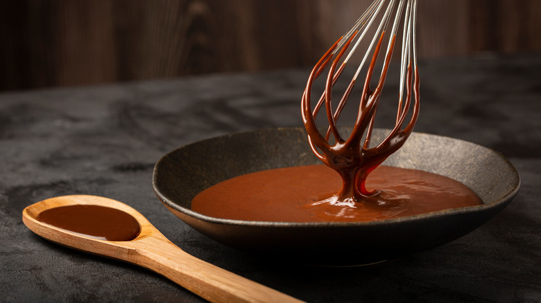 Bowl of melted chocolate with whisk and wooden spoon