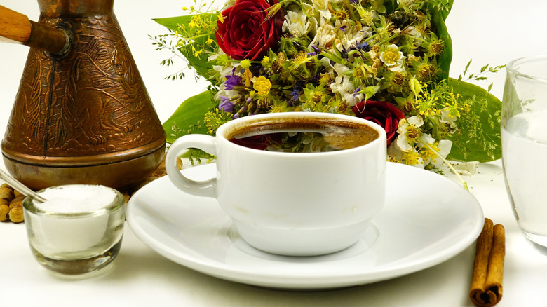 A cup of coffee on a saucer with a small bowl salt