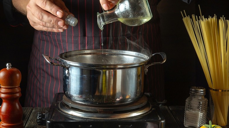 Cook adding oil to steaming pot