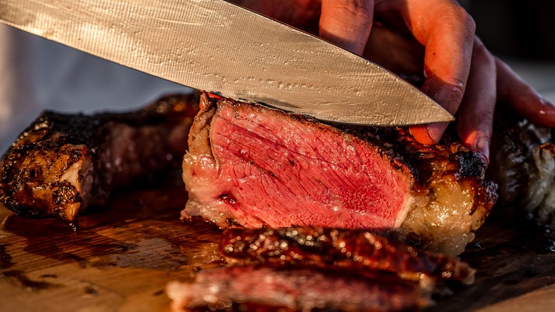 Person slicing a thick steak