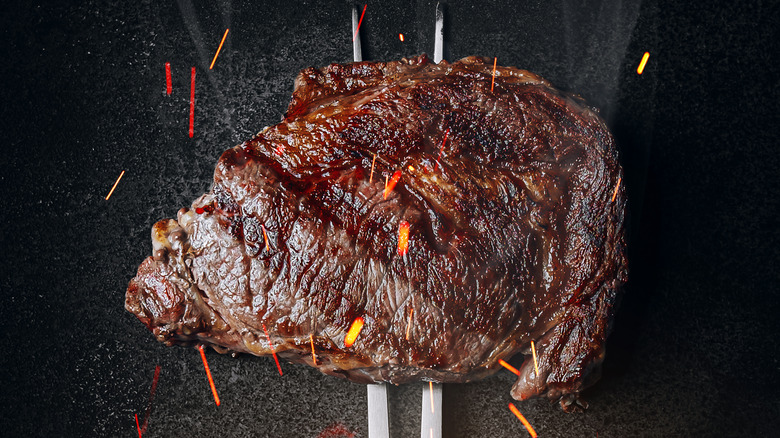 grilled stak on fork over roaring flames