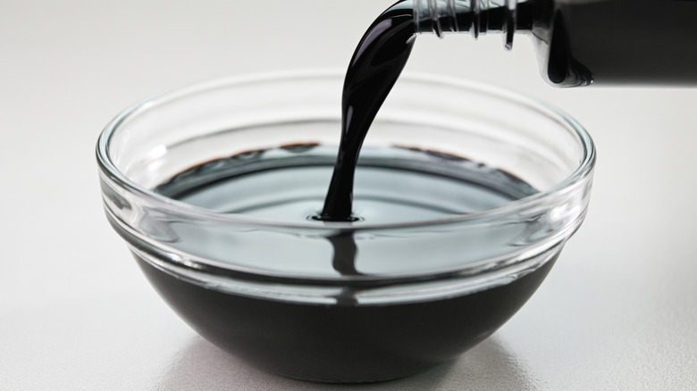 Pouring soy sauce into a bowl on gray table