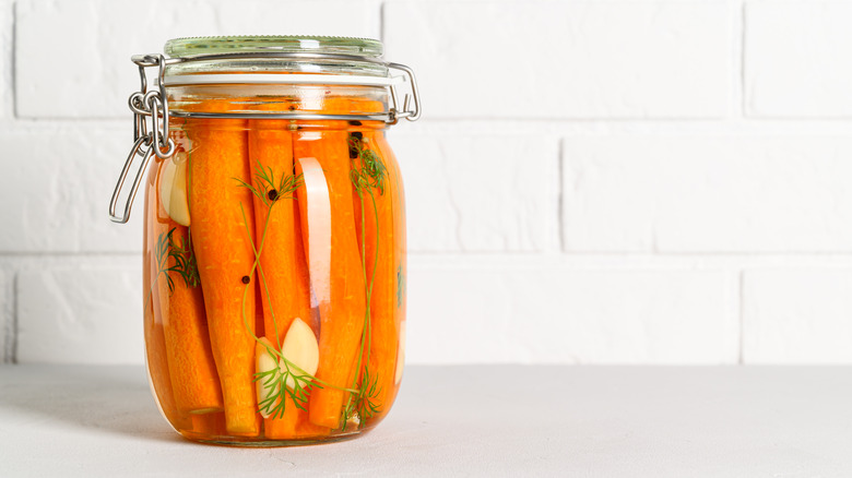 pickled carrots in a glass jar with herbs and spices
