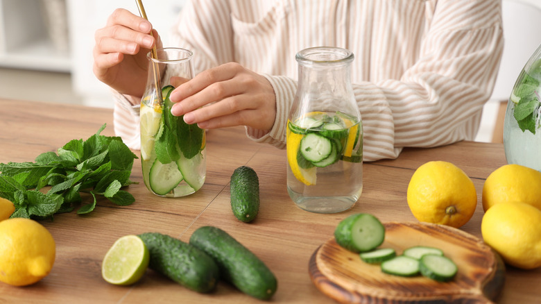 Person infusing water with cucumber, lemon, and mint