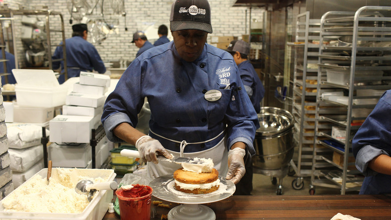A Whole Foods employee ices a cake