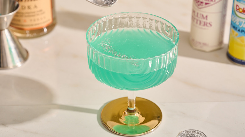 sprinkling glitter on green cocktail