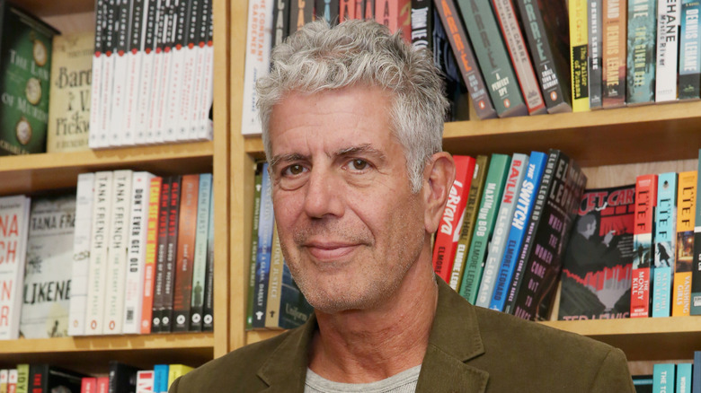 Anthony Bourdain in front of a bookstore bookshelf