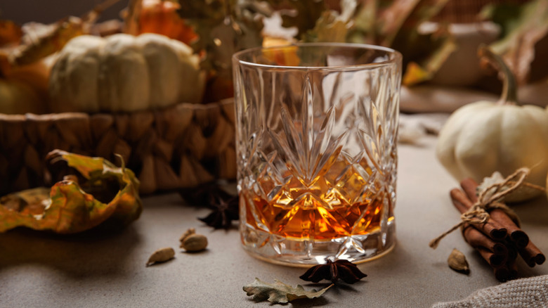 Glass of bourbon with pumpkins and spices