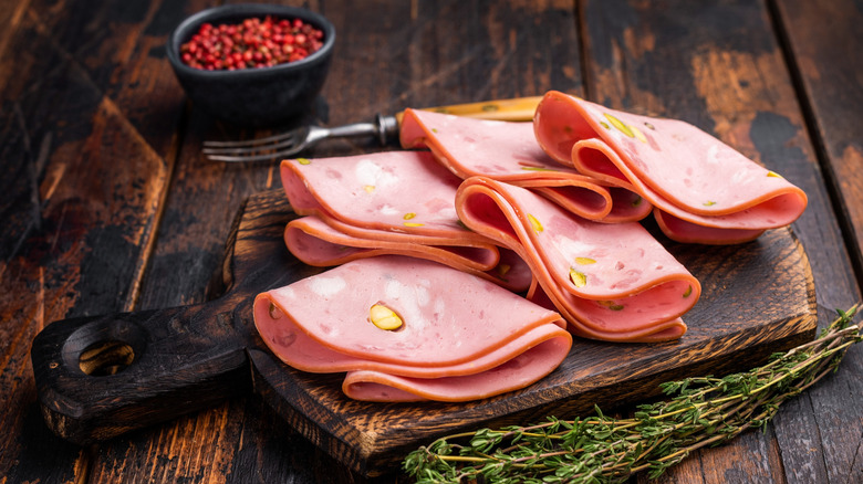 Mortadella slices with pistachios on wooden cutting board