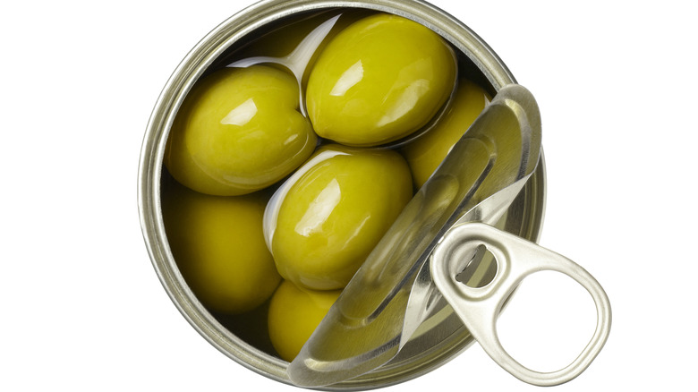 View from the top of a can of green olives with the pull-tab top partially open.