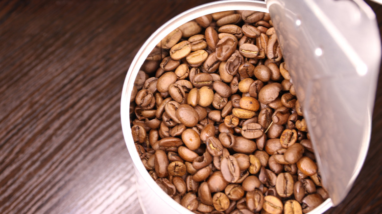A partially opened can of whole roasted coffee beans.