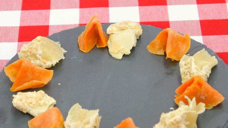Orange and beige fortune cookies, with the beige ones looking raw and crushed