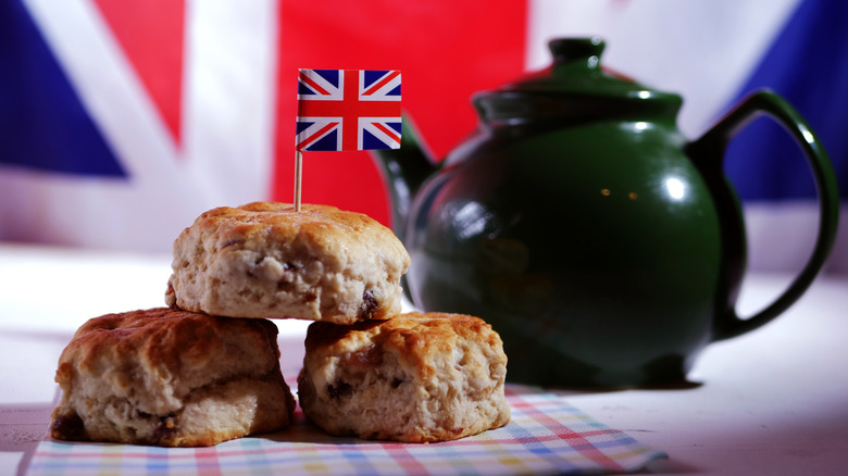 A pyramid of three scones with a UK flag in them, and a teapot and UK flag in the background
