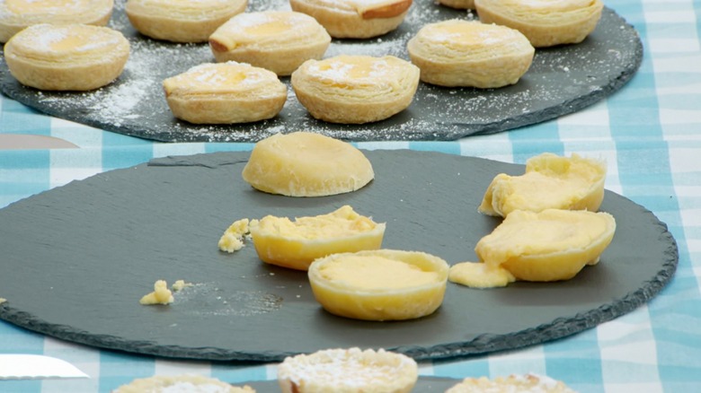 Five small tartlets on a black plate. Four are undercooked and liquid, and one is upside down
