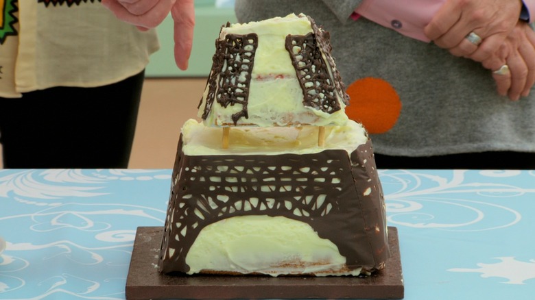 A yellow-colored cake that looks like the bottom half of the Eiffel Tower, with ironwork made of chocolate