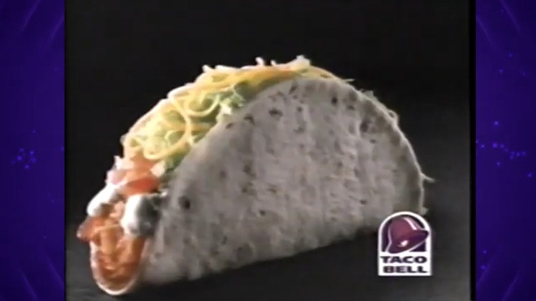 Taco Bell's BLT soft taco with bacon, lettuce, tomato, cheedar cheese, and white sauce with the Taco Bell logo in the corner