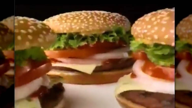 Three Burger King Whopper sandwiches with one patty, pepper jack cheese, onions, lettuce, and tomato.