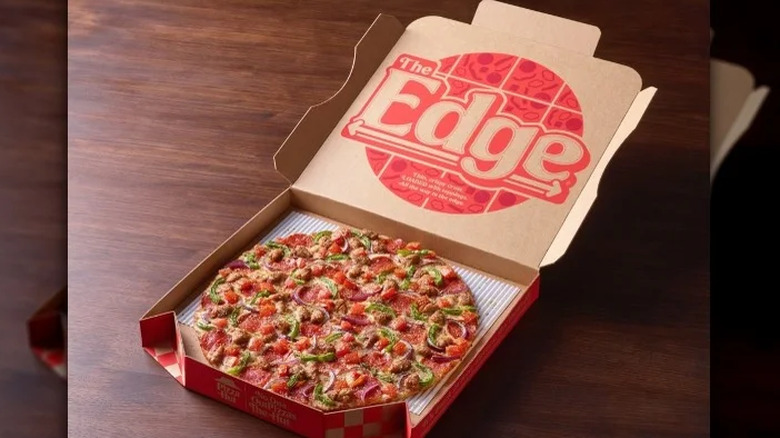 An open Pizza Hut box featuring The Edge branding on the top and a thin-crust pizza in the box.