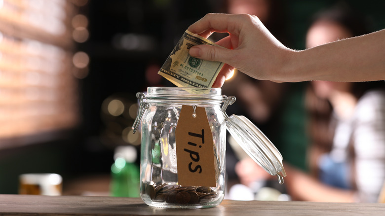 Hand puts tip in jar