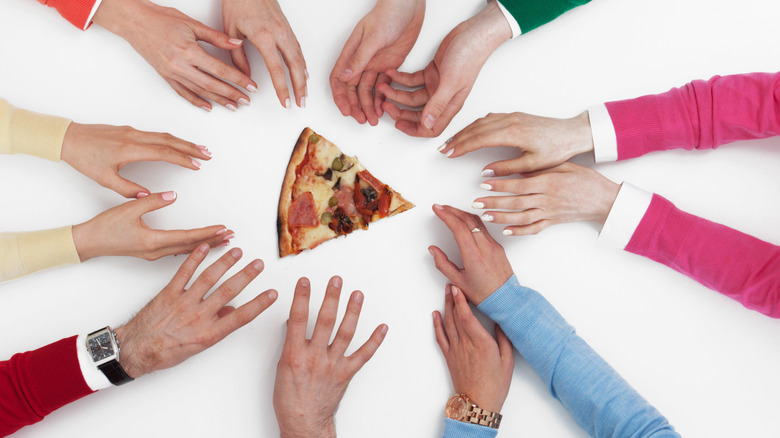 many hands reach for pizza