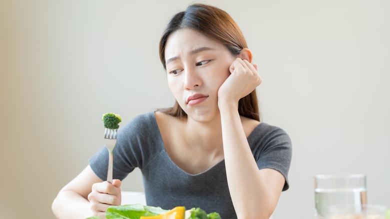 Tired woman looks at broccoli