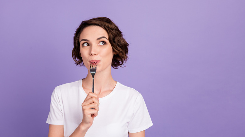 woman thinks while licking fork