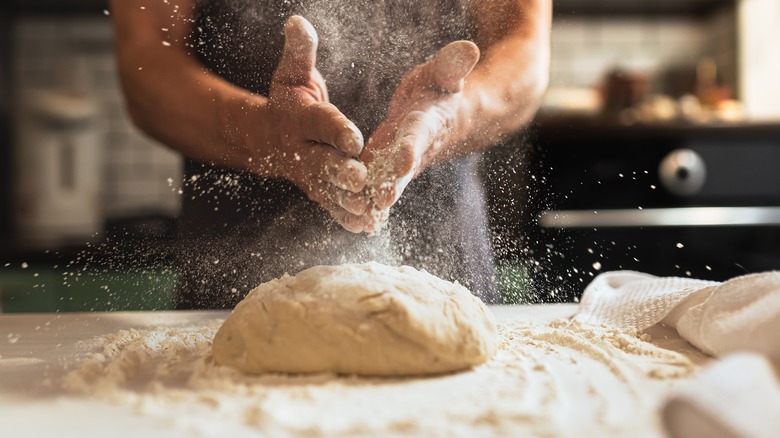 Hands making dough on table