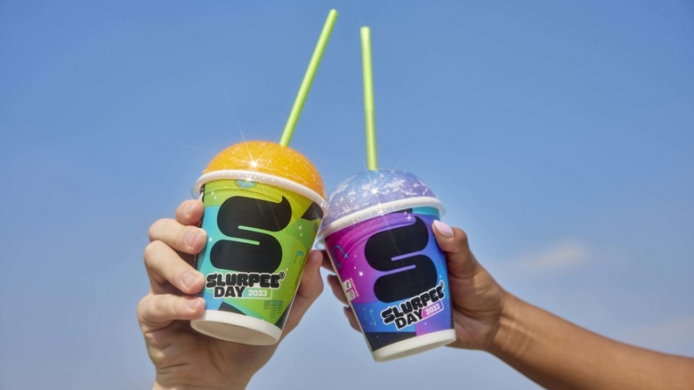 Two people holding up the new Slurpee cups