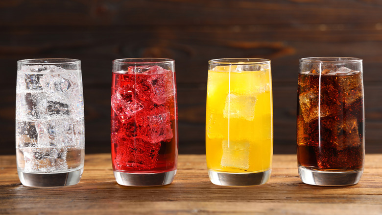 Four glasses of different soda flavors